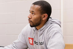 A male wearing a sociology sweatshirt sits in a classroom.